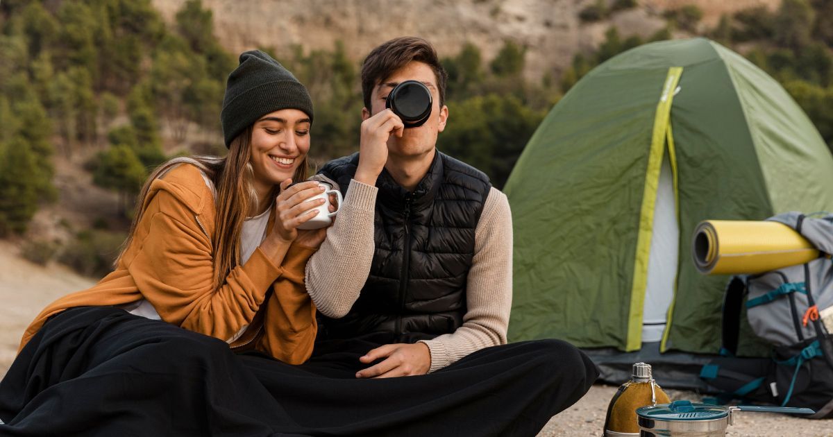 couple drinking hot drinks together outside camping