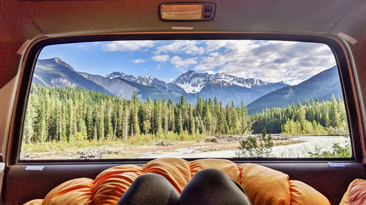 laying in the back of a vehicle looking out at the mountains