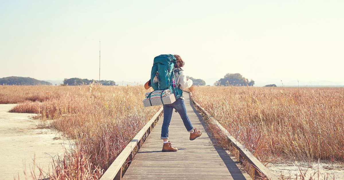 woman hiking on a wooden bridge with backpack