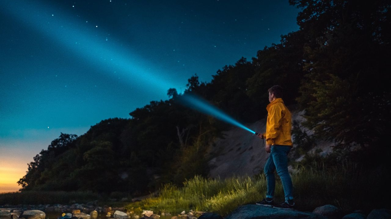 man shining a flashlight at the sky