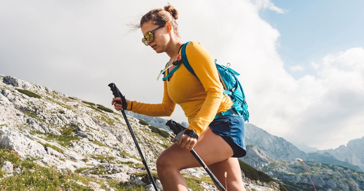 woman hiking in mountains with trekking poles