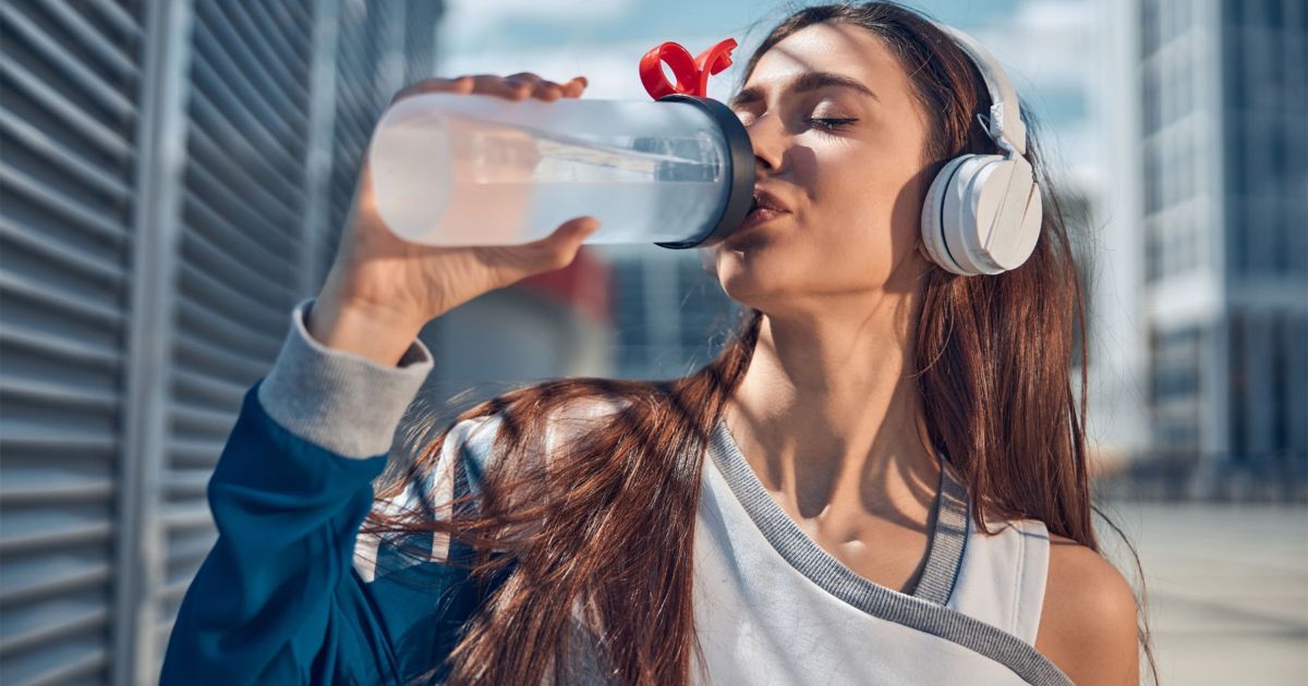 woman wearing headphones and drinking water