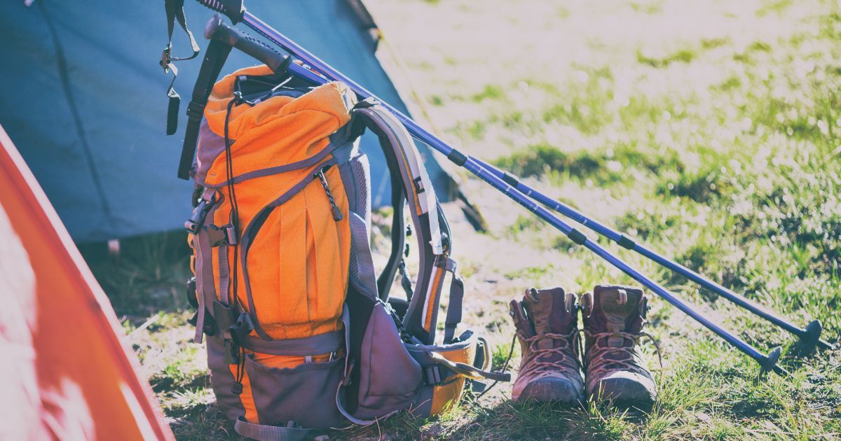 bacpack, trekking poles, boots, and tent in background