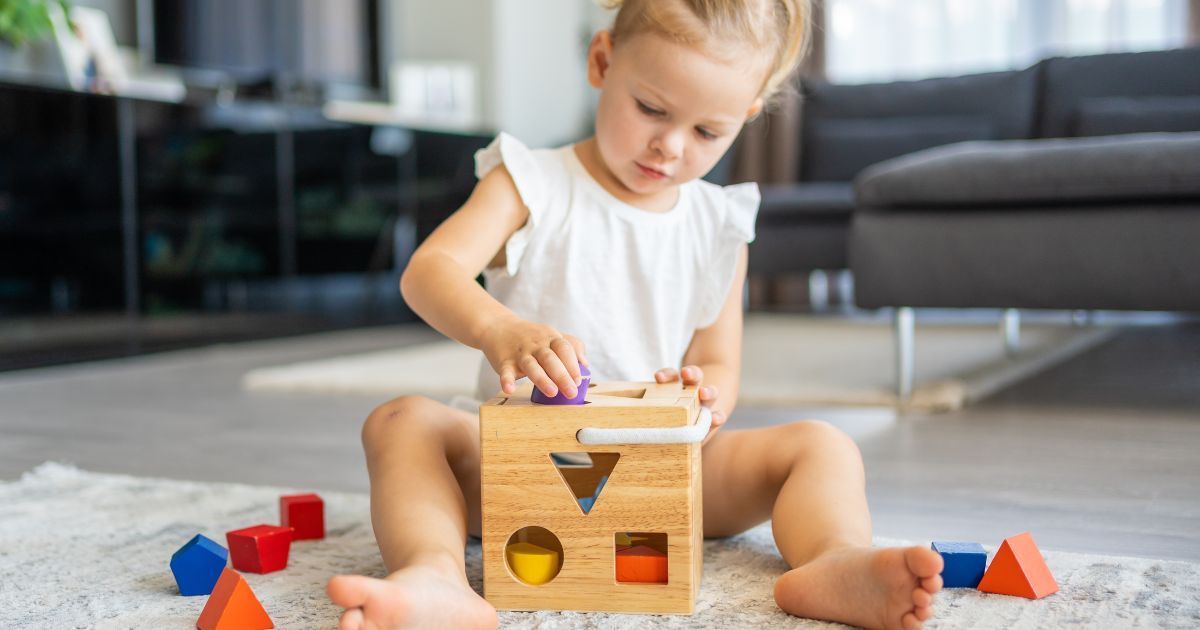 girl playing with shape sorter toy