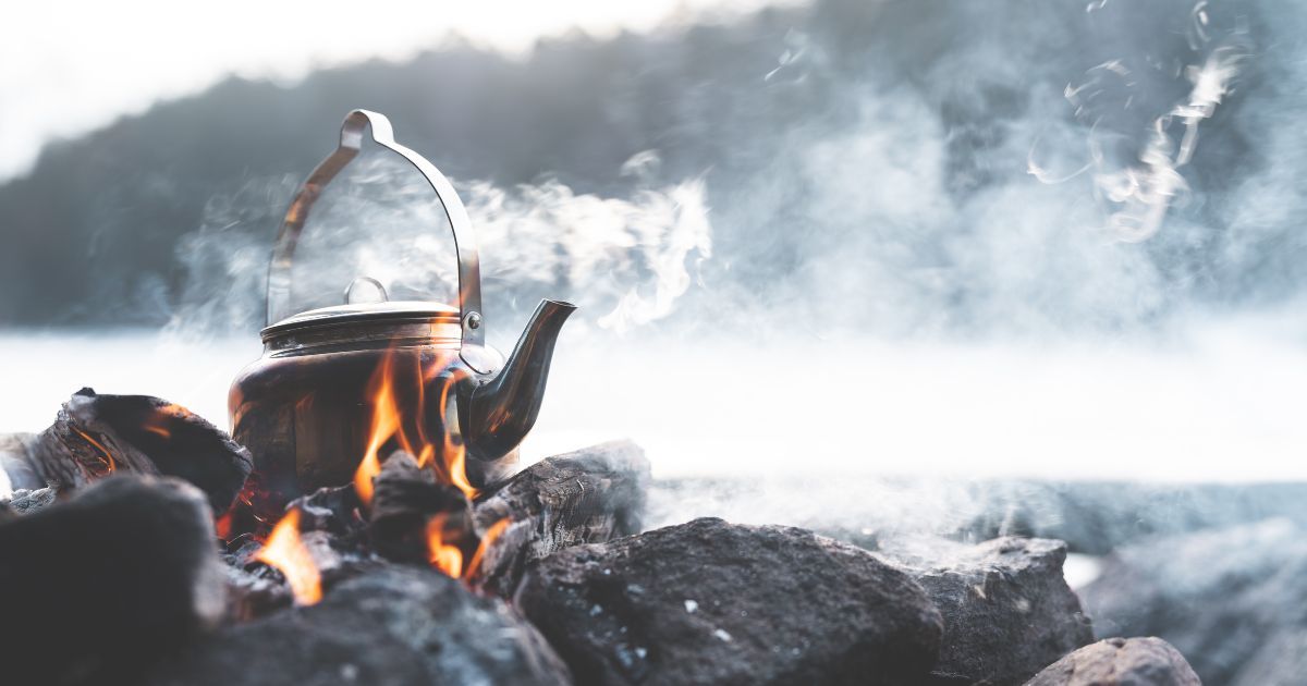 traditional stainless steel kettle on campfire