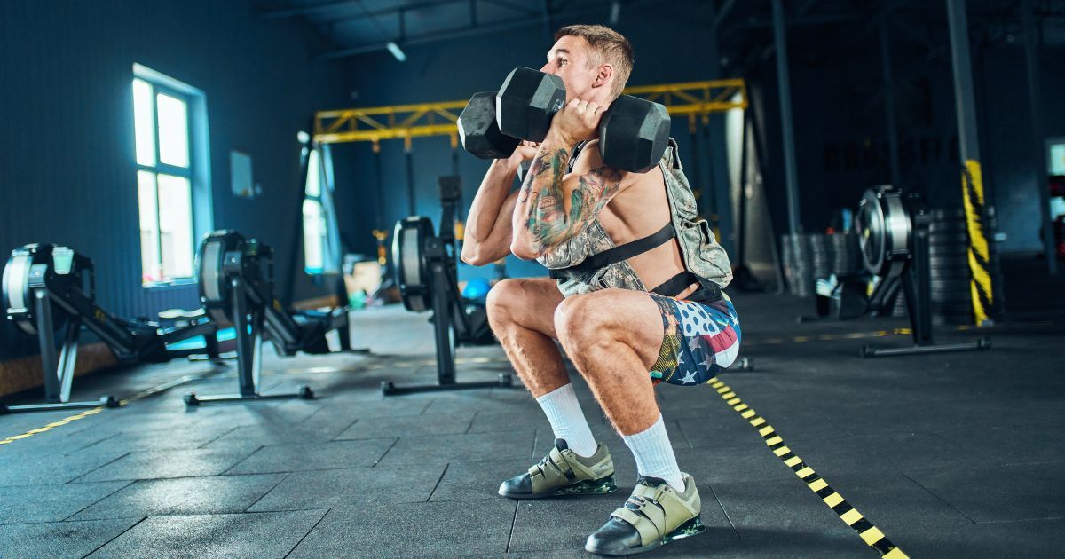 man doing dumbell squats with weight vest