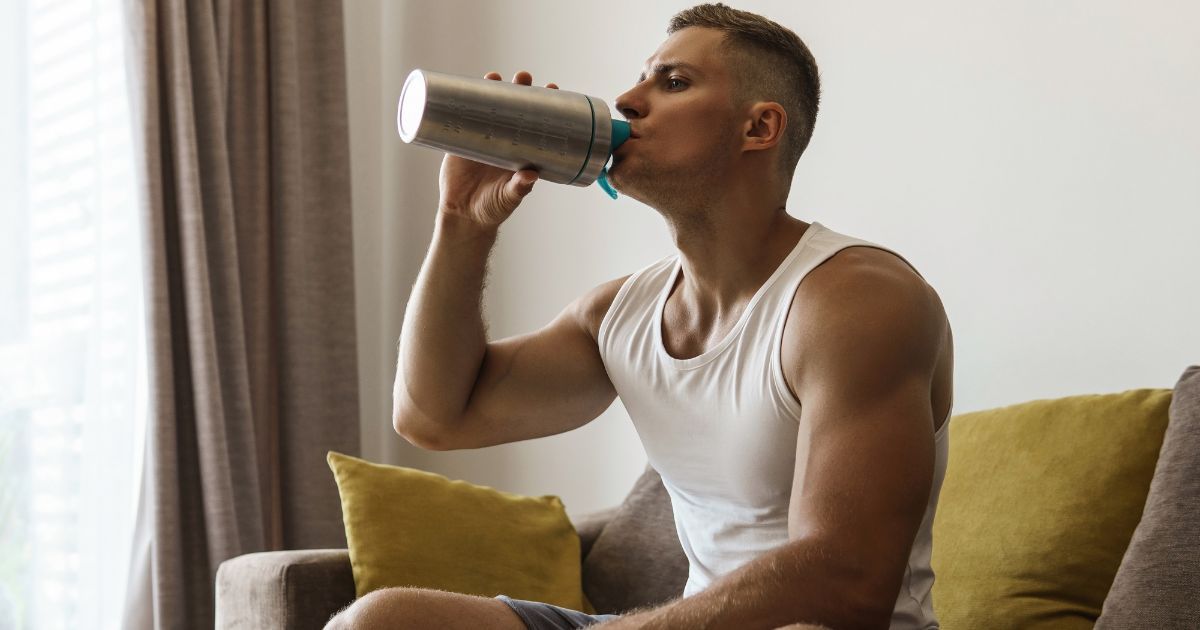 man on couch drinking from shaker cup