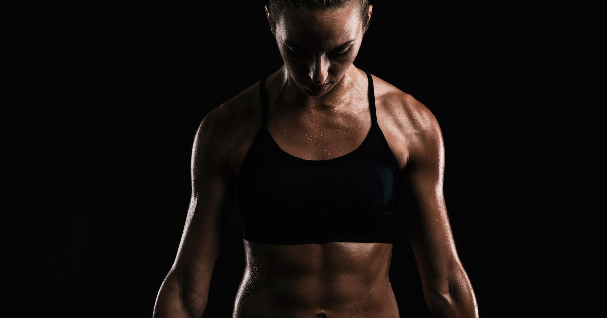 muscular woman against dark background