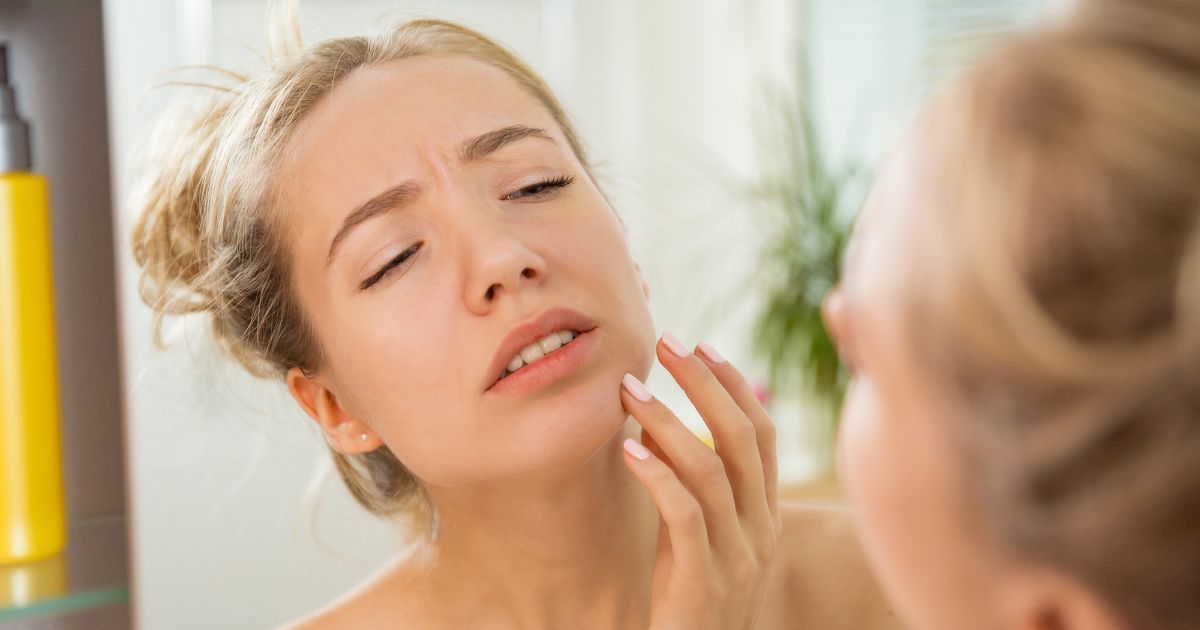 woman inspecting skin issue on face