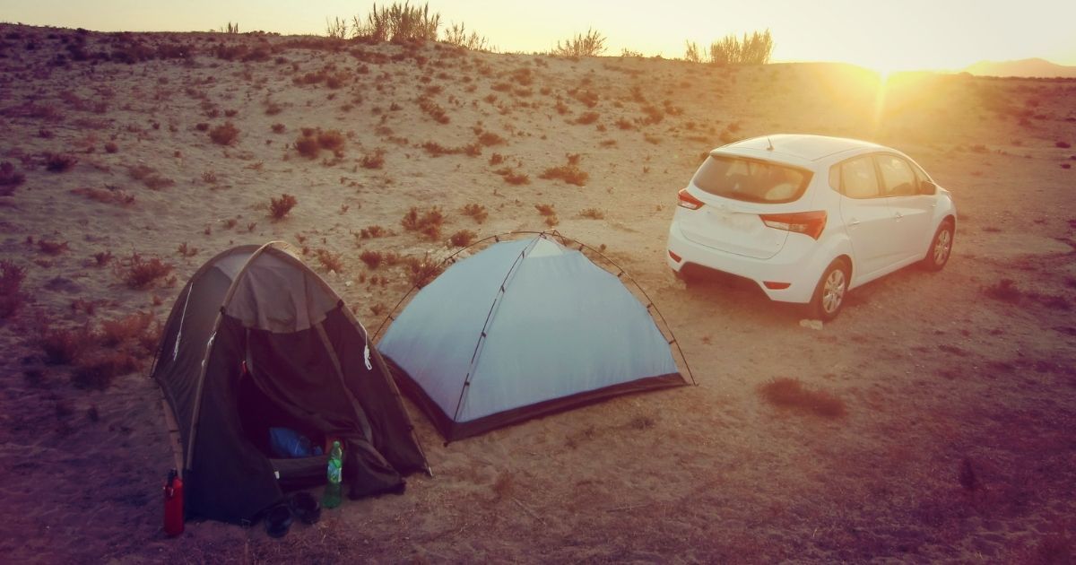 couple tents set up next to car in desert