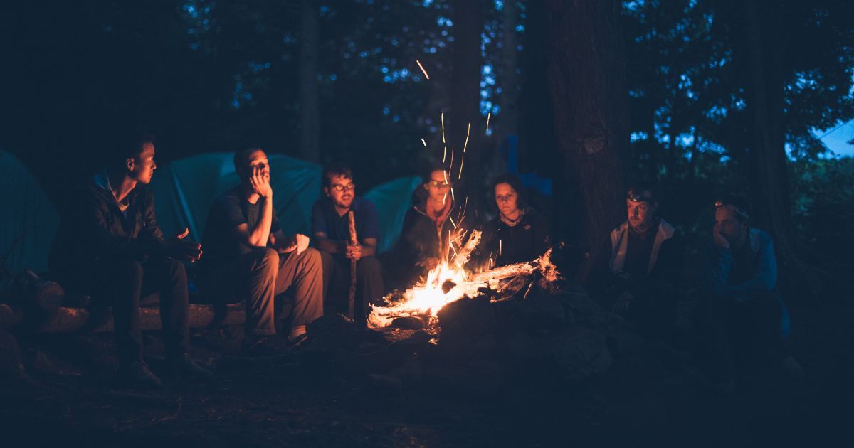 group of friends camping by fire
