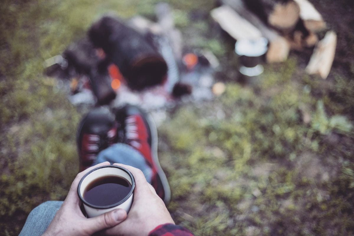 holding a mug with coffee while camping