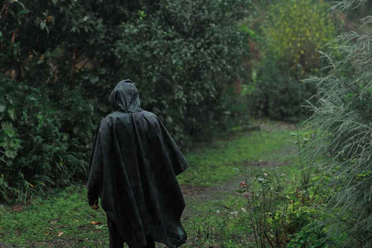 guy with poncho walking through forest